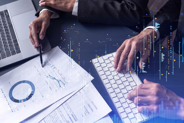 Dos comerciantes, un hombre y una mujer, investigan datos históricos para predecir el comportamiento del mercado de valores Concepto de comercio por Internet Forex y gráfico de holograma financiero sobre la mesa con los documentos