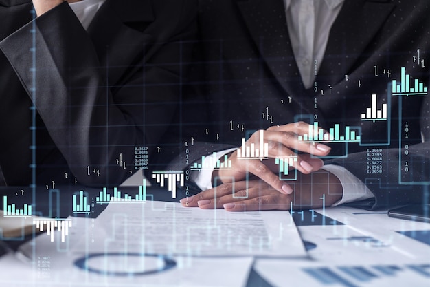 Dos comerciantes que investigan datos históricos para predecir el comportamiento del mercado de valores Mujeres en el concepto de negocio comercial Forex y gráfico de holograma financiero sobre la mesa con el documento