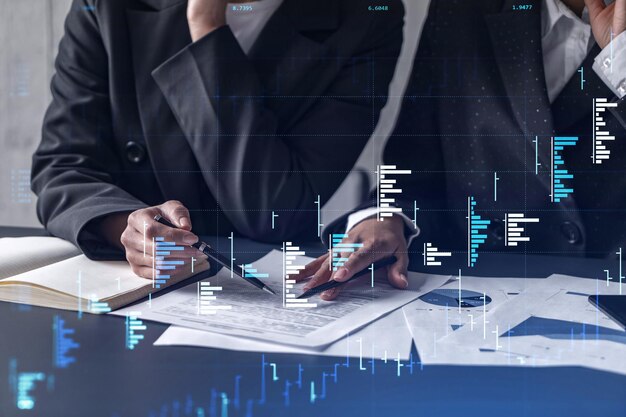 Dos comerciantes que investigan datos históricos para predecir el comportamiento del mercado de valores Mujeres en el concepto de negocio comercial Forex y gráfico de holograma financiero sobre la mesa con el documento