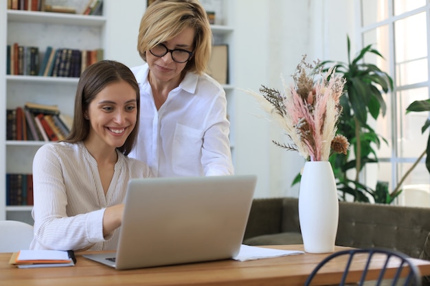 Dos compañeras trabajando con una computadora portátil y discutiendo un nuevo proyecto.