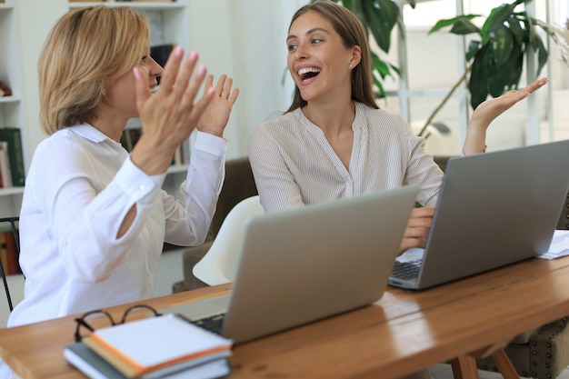 Dos compañeras trabajando con una computadora portátil y discutiendo un nuevo proyecto.