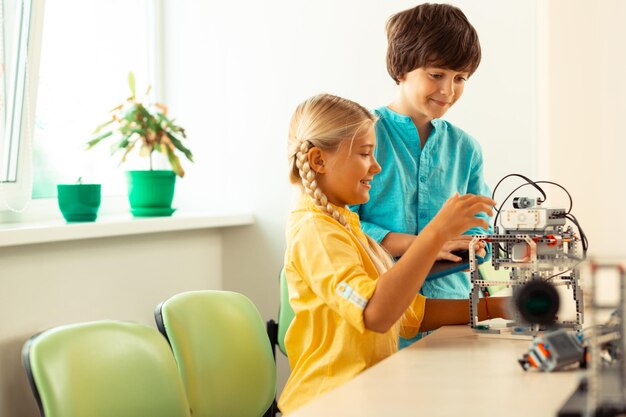 Dos compañeros de clase jugando con un robot que construyeron