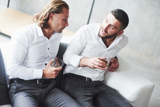 Dos compañeros de equipo conversan en el recreo y beben whisky