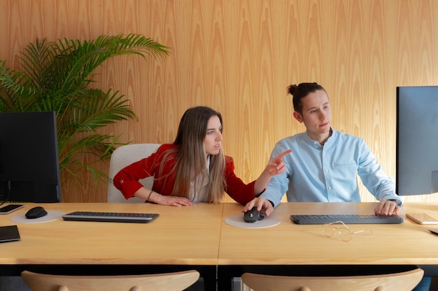 Dos compañeros de trabajo hablando de nuevos proyectos en la computadora