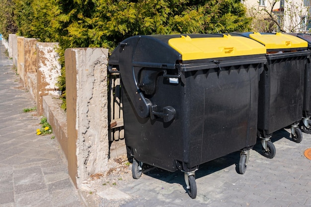 Dos contenedores de basura con tapas amarillas están a lo largo de la pared de hormigón