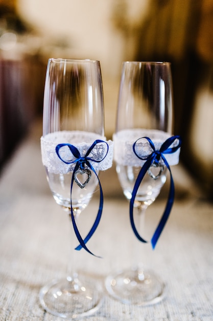 Dos copas de boda están decoradas con cintas azules y corazones.