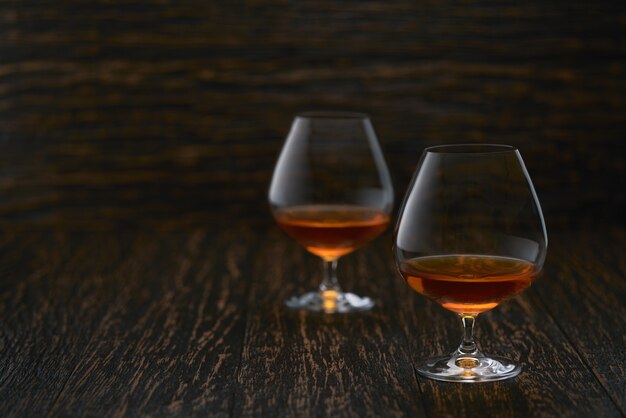 Dos copas de brandy o coñac en una mesa de madera con espacio de copia.