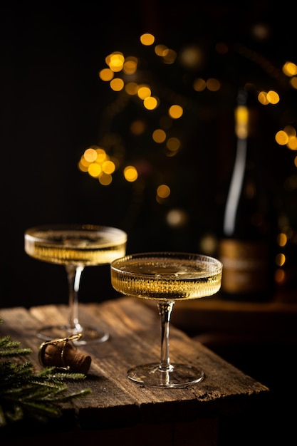 Dos copas de champán y una botella contra los fuegos artificiales y las luces navideñas de fondo oscuro