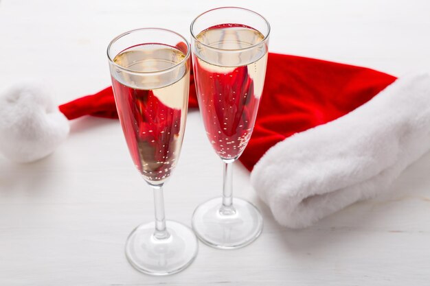 Dos copas de champán y un gorro de Papá Noel, fondo claro. Concepto de fiesta de navidad