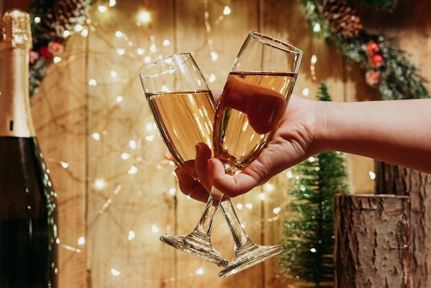 Dos copas de champán en una mano sobre el fondo de las decoraciones navideñas