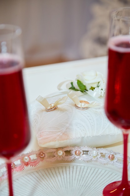 Dos copas de champaña y almohada con anillos de boda