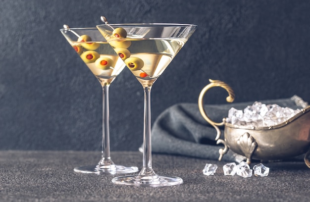 Dos copas de cóctel de martini adornado con aceitunas verdes