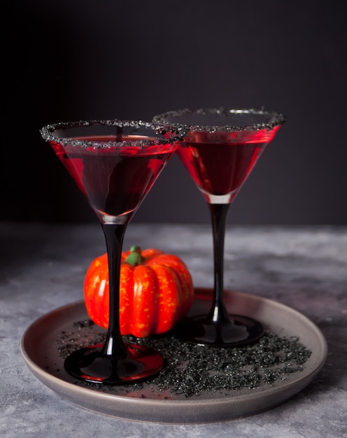 Dos copas con cóctel rojo para la fiesta de Halloween en la oscuridad