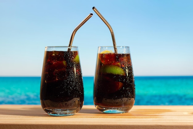 Dos copas de cócteles Cuba Libre en la playa de verano