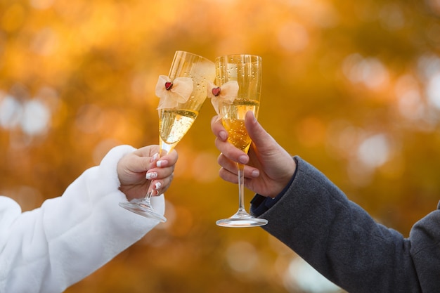 Dos copas decoradas con champán en manos de la novia y el novio.