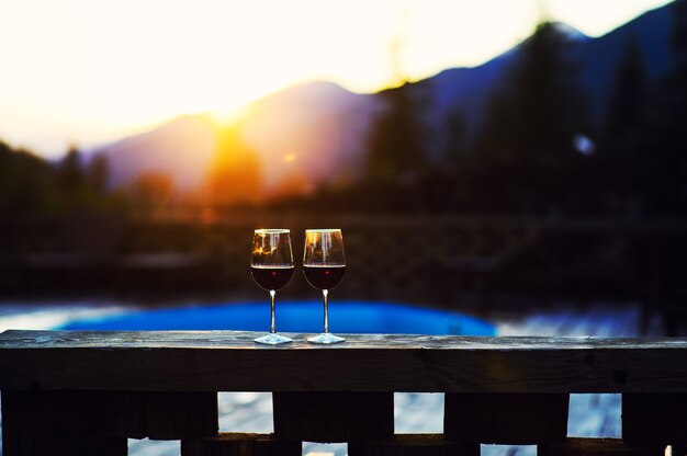 Dos copas de vino al atardecer espectacular cielo sobre fondo de paisaje de montaña