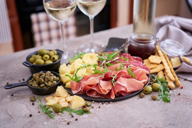 Dos copas de vino blanco y un plato de carne antipasto italiano en la cocina doméstica