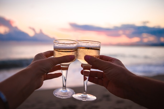 Dos copas de vino blanco en la playa al atardecer