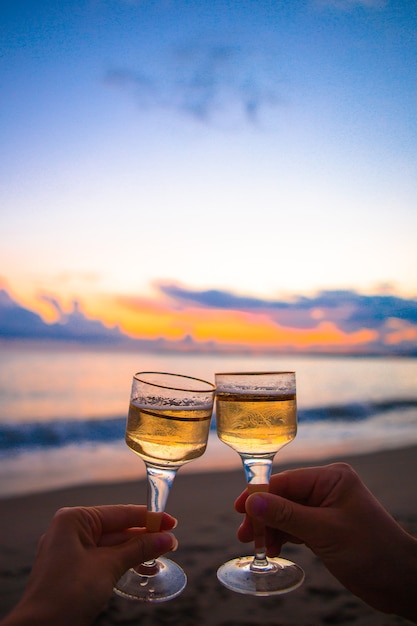 Dos copas de vino blanco en la playa al atardecer