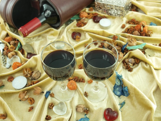 Dos copas de vino con una botella de vino sobre una mesa con una servilleta y una botella de vino encima.