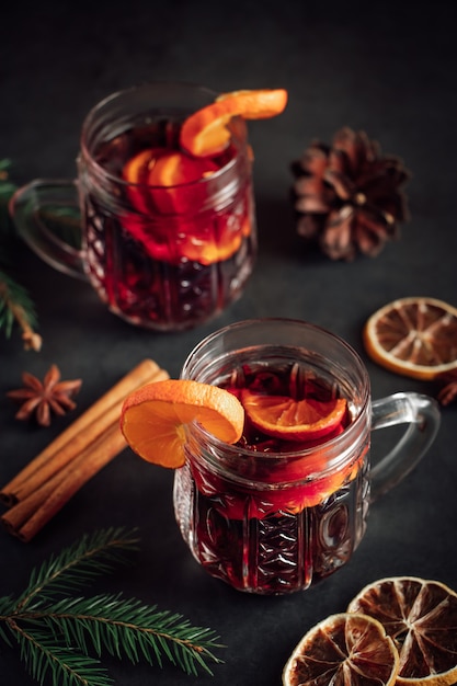 Dos copas de vino caliente caliente con frutas y especias sobre fondo oscuro Bebida de vacaciones de invierno