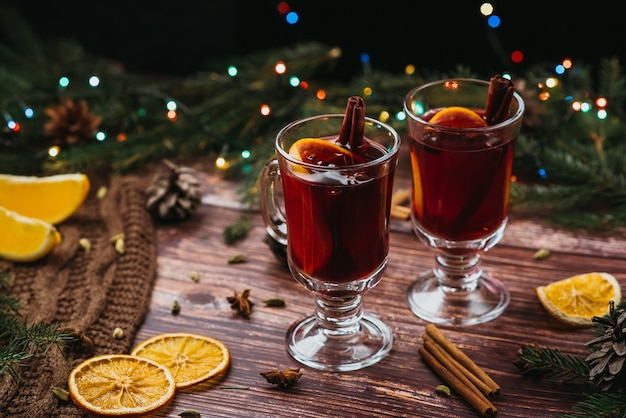 Dos copas con vino caliente en una mesa de madera con ramas de abeto año nuevo