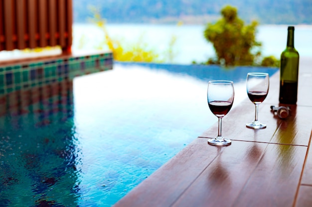 Dos copas de vino tinto cerca de la piscina con una vista espectacular del mar.