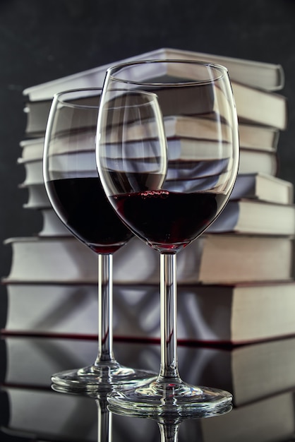 Dos copas de vino tinto contra una pila de libros, primer plano. Espacio libre para texto.