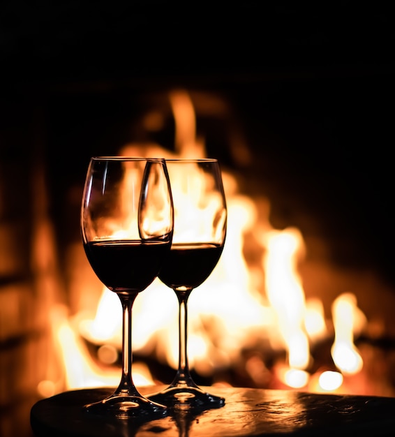 Dos copas de vino tinto en el fondo de las luces de la chimenea