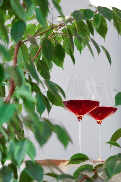 Dos copas de vino tinto en mesa de madera en cocina moderna y planta