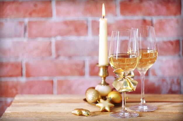 Dos copas de vino con velas y juguetes de Navidad sobre fondo de pared