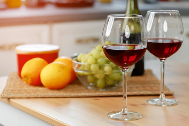 Dos copas de vino con vino tinto en la cocina de madera