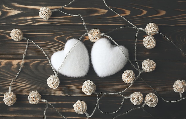 Dos corazones blancos con luces sobre fondo de madera Concepto de San Valentín Amor y foto romántica Postal para vacaciones