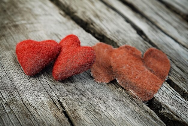 Dos corazones de fieltro rojo sobre un fondo de madera corazón roto amor para siempre concepto de boda