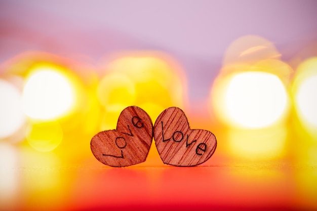 Dos corazones de madera sobre fondo rojo con luces borrosas. Concepto de amor para el día de san valentín.