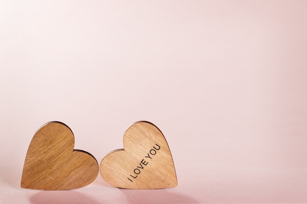 Dos corazones de madera sobre fondo rosa