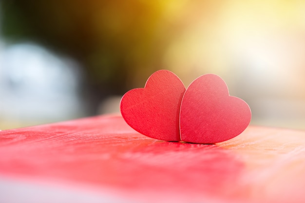 Dos corazones de madera sobre una mesa de madera roja borrosa, expresión de amor, festival de San Valentín, concepto de amor