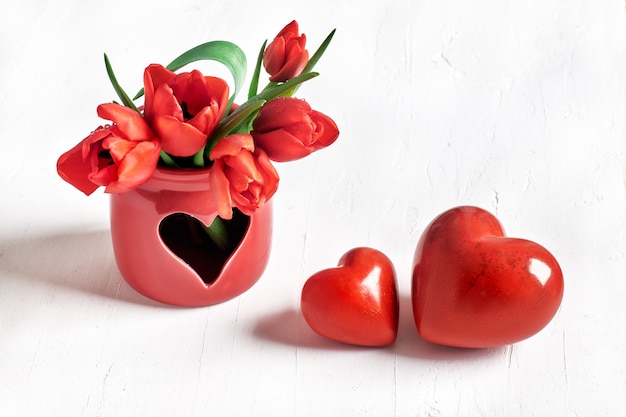 Foto dos corazones de piedra y ramo de tulipanes rojos sobre blanco