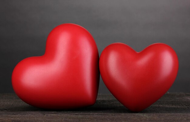 Dos corazones rojos decorativos en la mesa de madera sobre fondo gris