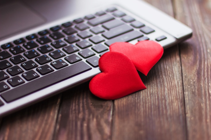 Foto dos corazones rojos se encuentran en una mesa de madera cerca de una computadora portátil, el día de san valentín