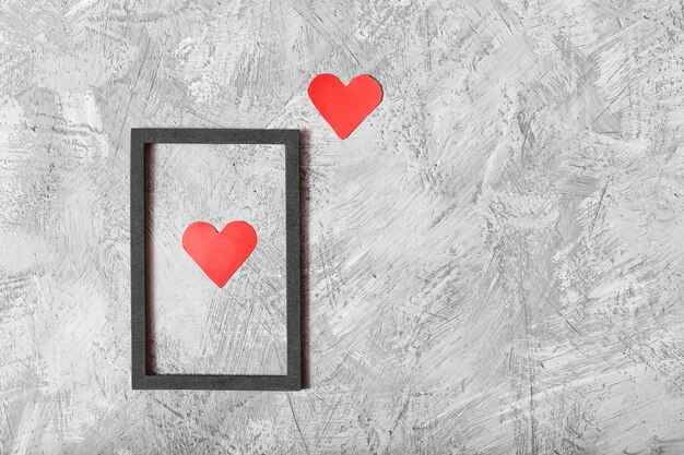 Dos corazones rojos en un marco sobre un fondo gris vista superior