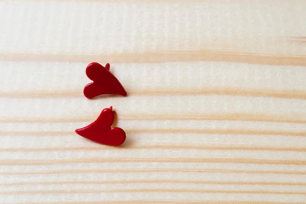 Dos corazones rojos metálicos sobre un fondo de madera