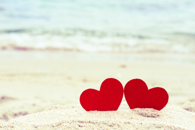 Foto dos corazones rojos en la playa de verano. amor, boda y concepto de día de san valentín