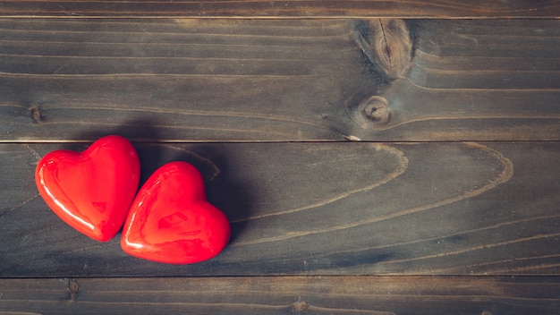 Dos corazones rojos sobre fondo de mesa de madera con espacio de copia