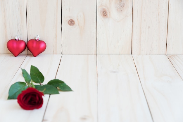 Foto dos corazones y rosa roja sobre fondo de madera