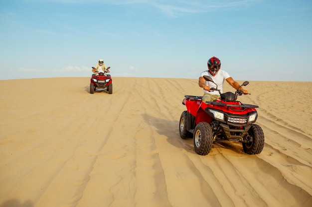 Dos corredores bajando de las dunas en atv.