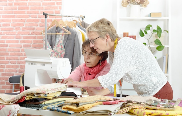 Dos costureras alegres trabajando juntas en su taller