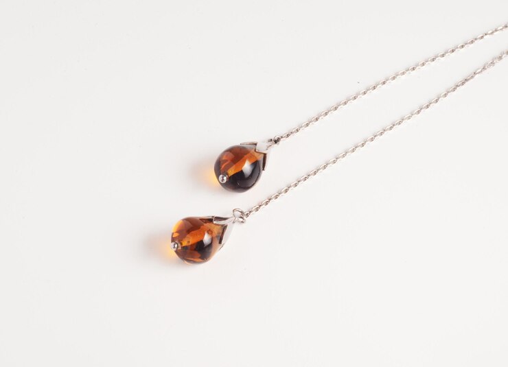 Dos cristales marrones en forma de gota de agua de un collar de lariat sobre un fondo blanco