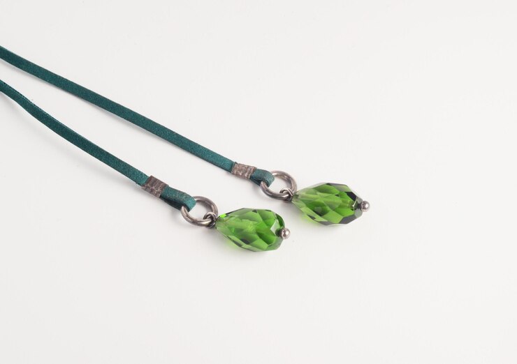 Dos cristales verdes en forma de gota de agua en la correa de cuero falso verde del collar de lariat