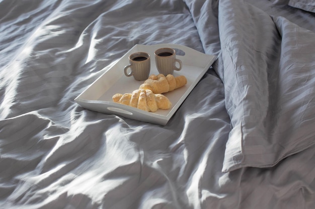 Dos croissants y dos tazas de café en la cama